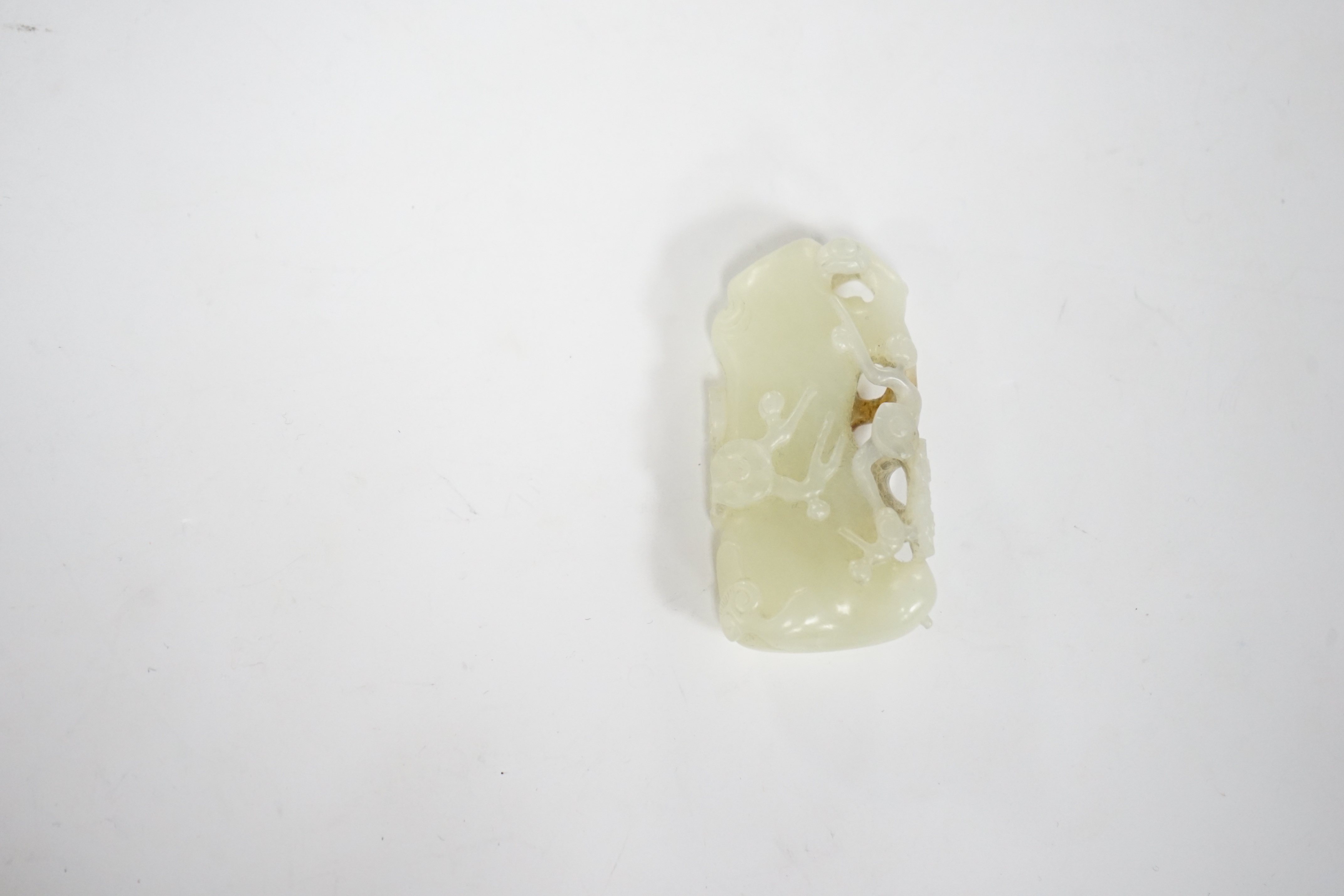 A Chinese pale celadon and russet jade carving of a prunus bough, 5.4cm